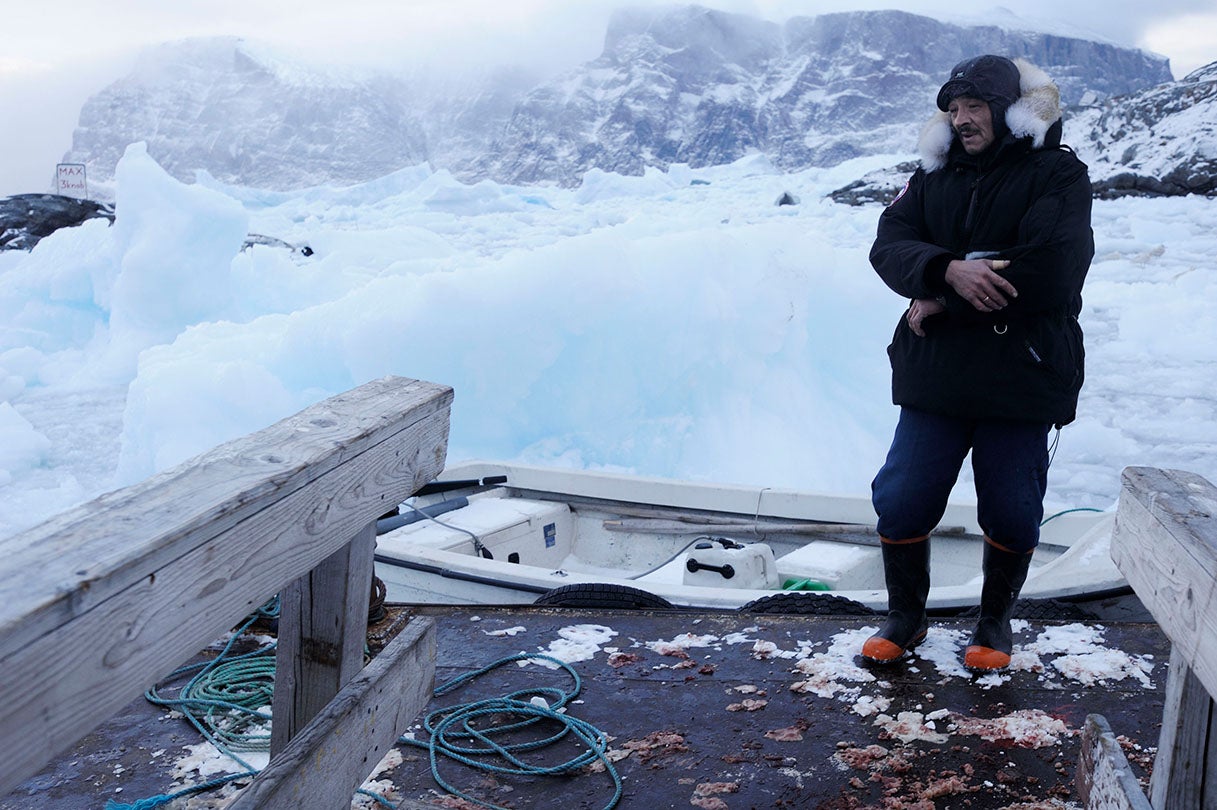 Seal hunter Paalu trying to free his skiff from the frozen ice in the harbor of Uummannaq, Greenland  2009