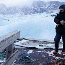 Seal hunter Paalu trying to free his skiff from the frozen ice in the harbor of Uummannaq, Greenland  2009